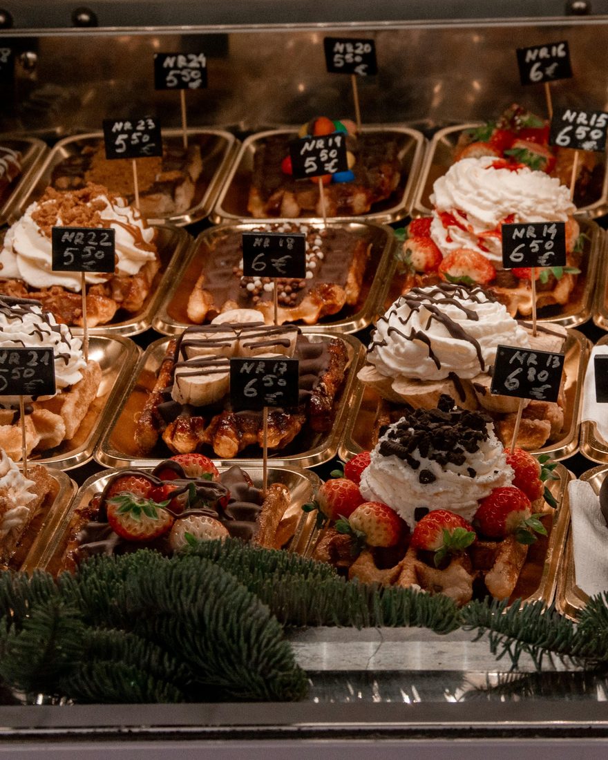 Vitrine met Brusselse wafels met slagroom, aardbeien en chocolade, met handgeschreven prijskaartjes