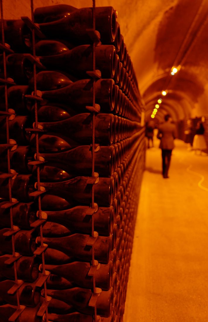 Lange gang in een champagnekelder met duizenden liggende flessen in metalen rekken