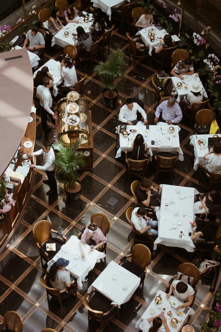 Bovenaanzicht van een chic restaurant met witte tafelkleden, obers en orchideeën