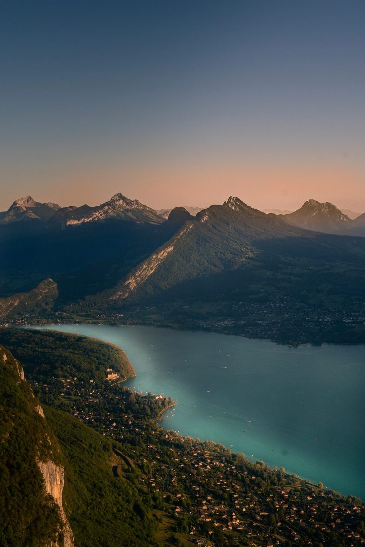 Uitzicht vanaf de bergen over het turquoise meer van Annecy met dorpen aan de oever