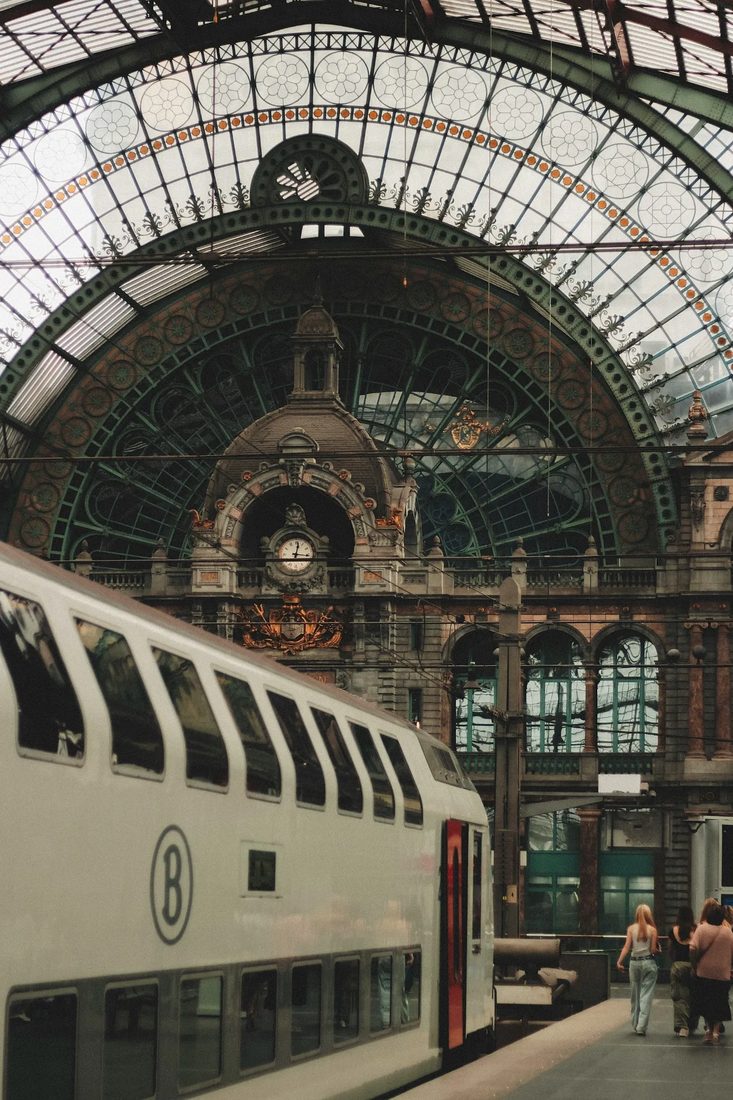 Trein langs het perron onder de monumentale glazen overkapping van Antwerpen-Centraal