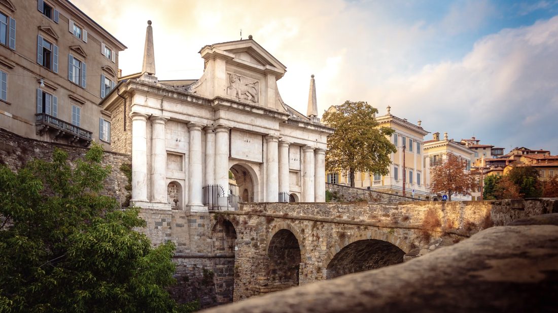 Marmeren stadspoort met zuilen aan het einde van een oude stenen brug in Bergamo
