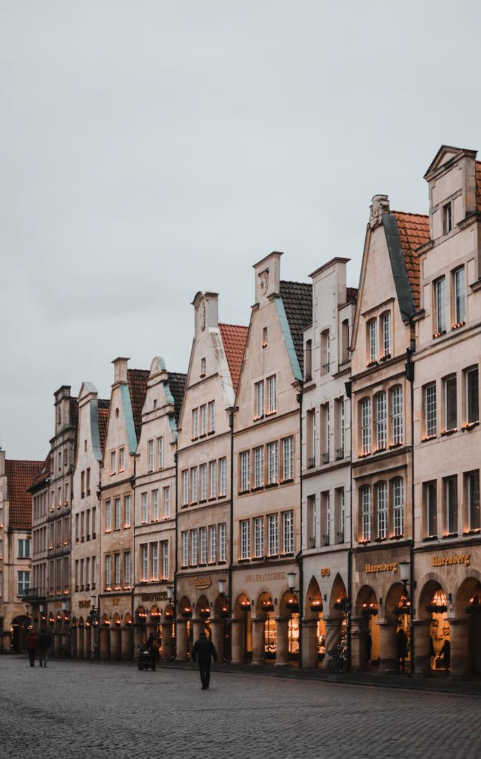 Rij historische geveltjes met verlichte winkels langs de Prinzipalmarkt in Münster