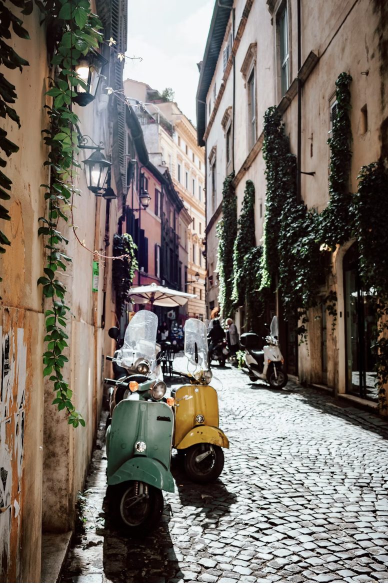 Groene en gele vespa's geparkeerd in een geplaveide straat in Rome