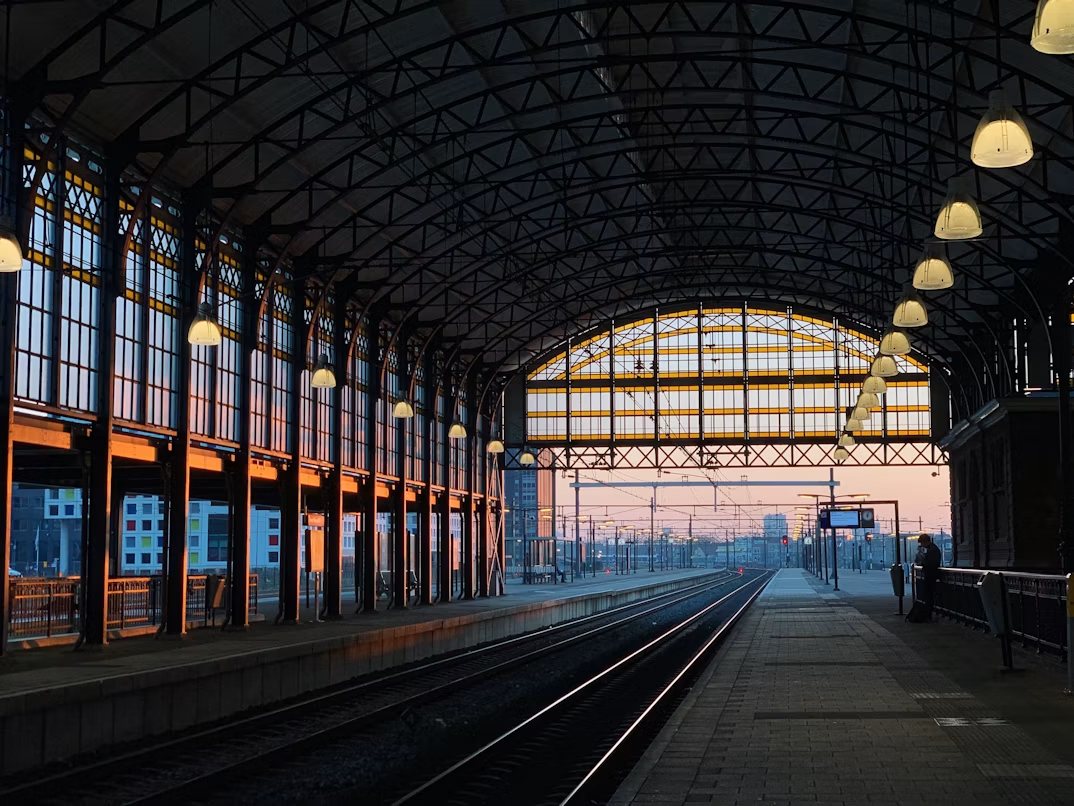 Leeg overkapt perron met sporen bij zonsopkomst op een Nederlands station