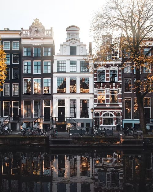 Amsterdamse grachtenpanden met herfstkleuren weerspiegeld in het water