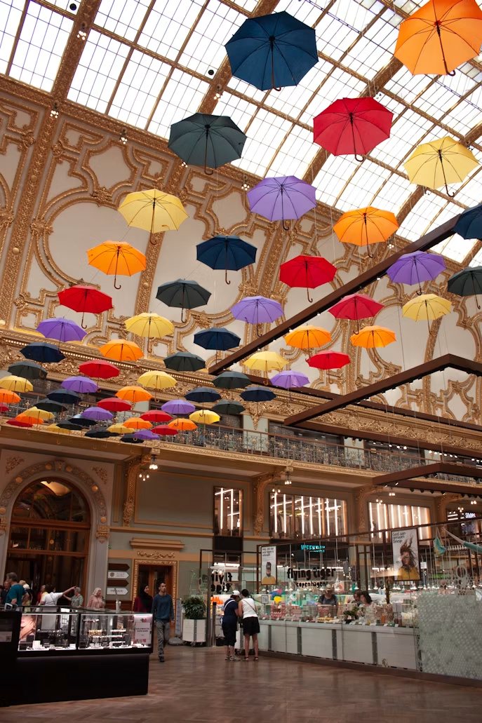 Kleurrijke paraplu's onder het glazen dak van een monumentale winkelgalerij in Antwerpen