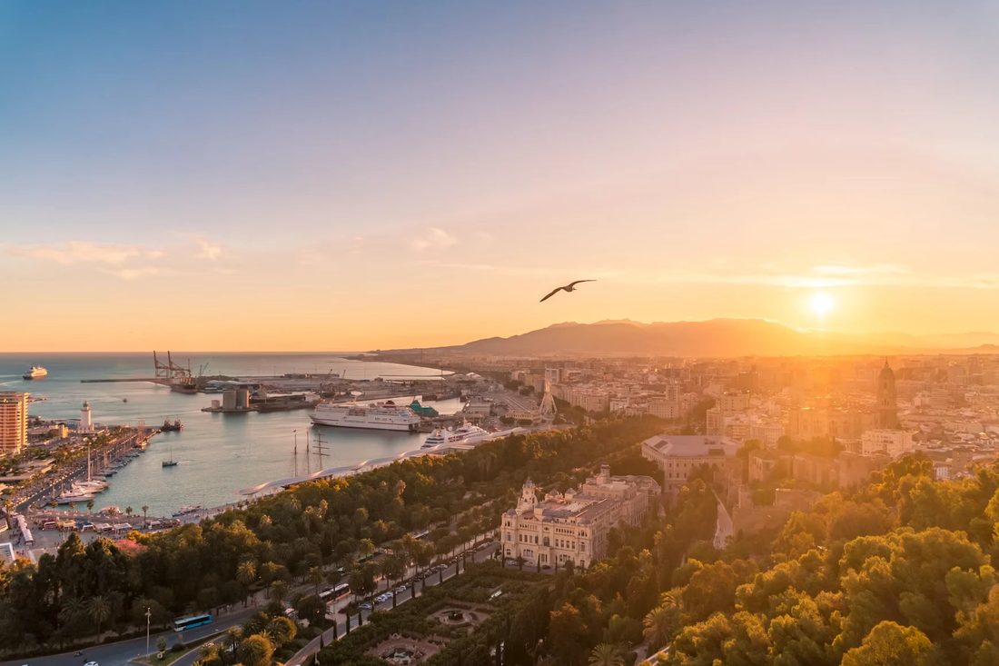 Uitzicht over Málaga bij zonsondergang met de haven, het park en de kathedraal
