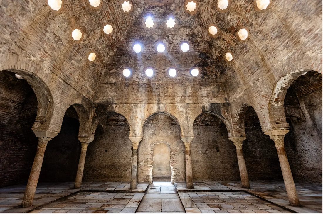 A historic hammam with brick arches, columns and star-shaped openings in the vaulted ceiling