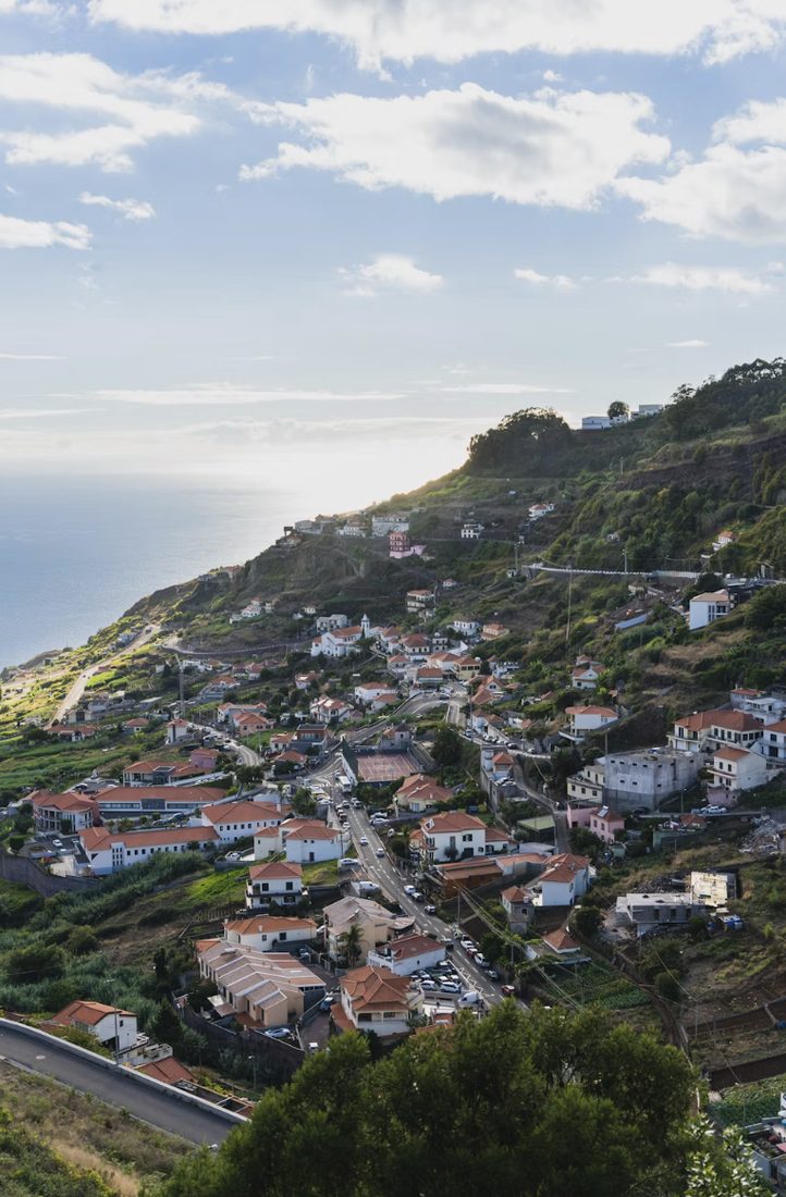 Wit dorp met oranje daken tegen een groene berghelling boven de oceaan op Madeira