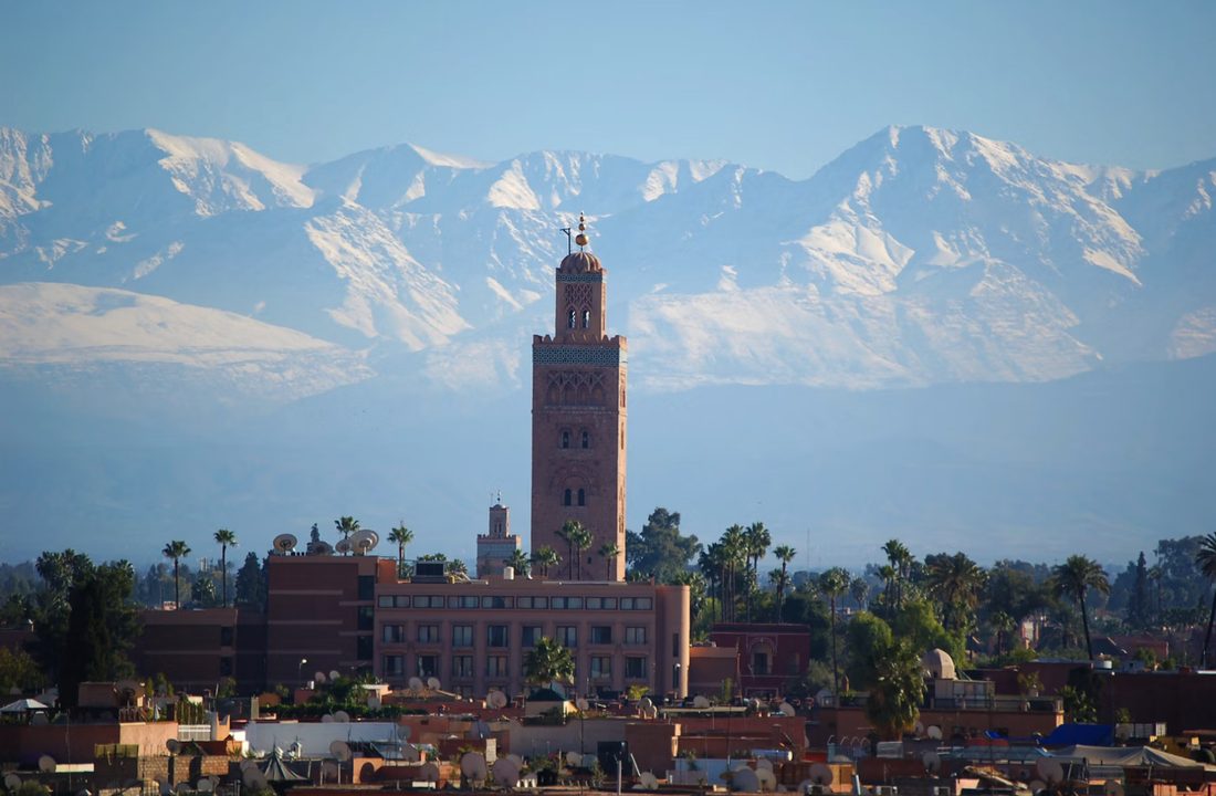 De minaret van de Koutoubia-moskee in Marrakech met daarachter de besneeuwde Atlas